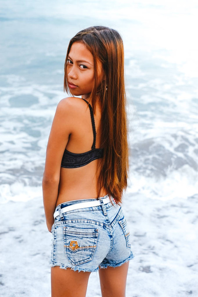 Young beautiful Asian girl standing in the water on the beach - Фото, зображення