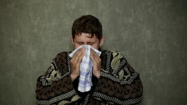 The man sneezes, runny nose, fever. A man in a dressing gown sneezes into his handkerchief. - Footage, Video