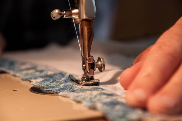 Швейна машина, процес шиття, жіночі руки тримають тканину до
 - Фото, зображення