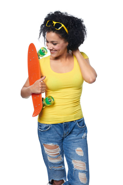 Happy female in distressed jeans with skateboard - Photo, Image
