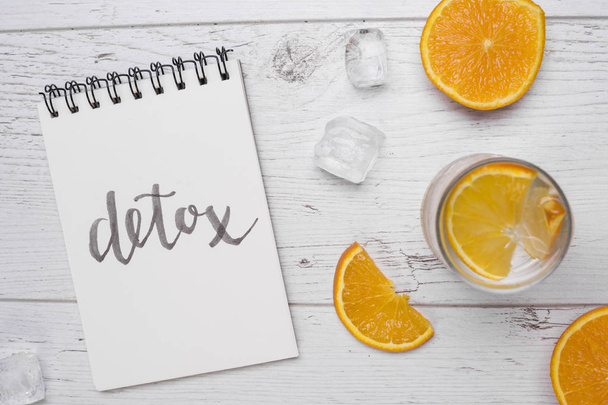 Detox lettering. White wooden background with oranges and drink. - Фото, изображение