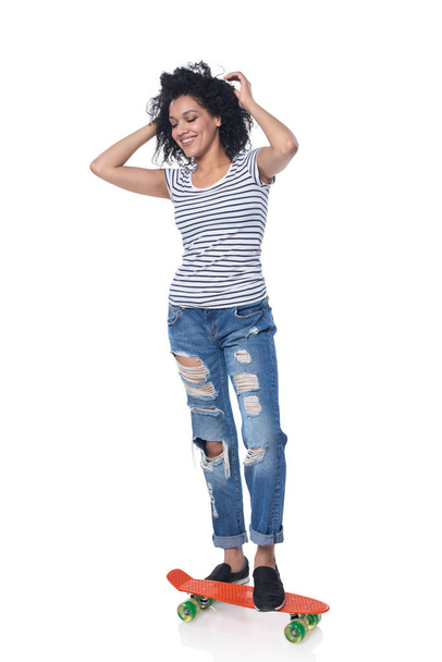 Happy female in distressed jeans with skateboard - Fotoğraf, Görsel