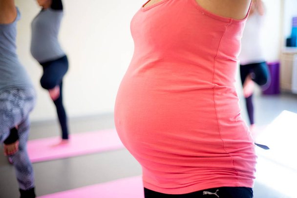 Pregnant woman does fitness exercises - Фото, изображение