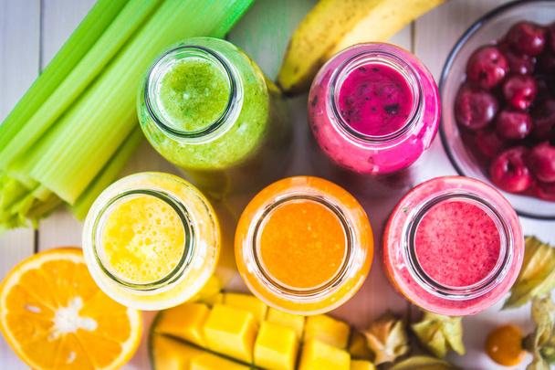 Multicolored smoothies in bottles of mango, orange, banana, cele - Фото, изображение