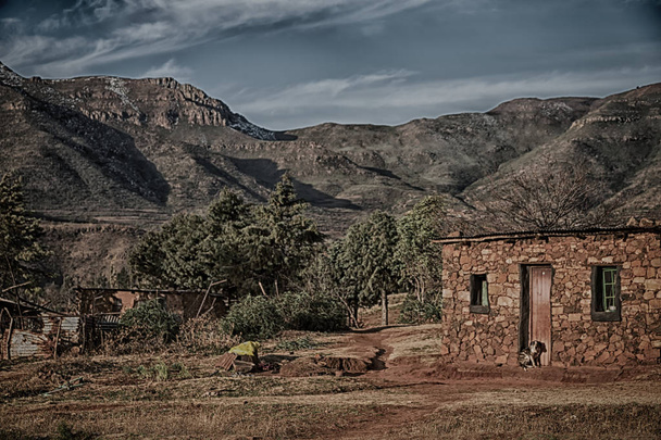 desenfoque en lesotho malealea pueblo de la calle cerca de la montaña y campo de coultivation
 - Foto, Imagen
