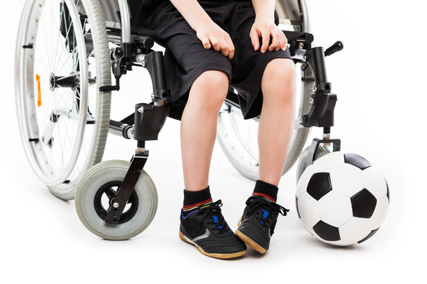 Disabled child boy sitting on wheelchair holding soccer ball - Фото, зображення