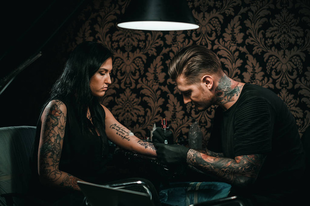 Profesjonalny tatuażysta robi tatuaż na ręce młodej dziewczyny - Zdjęcie, obraz