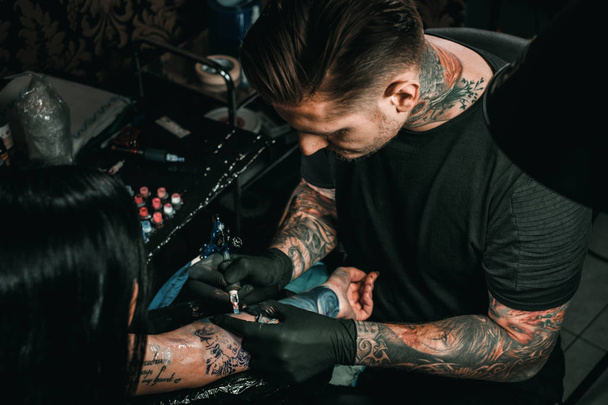 Професійний художник татуювання робить татуювання на руці молодих дівчат
 - Фото, зображення