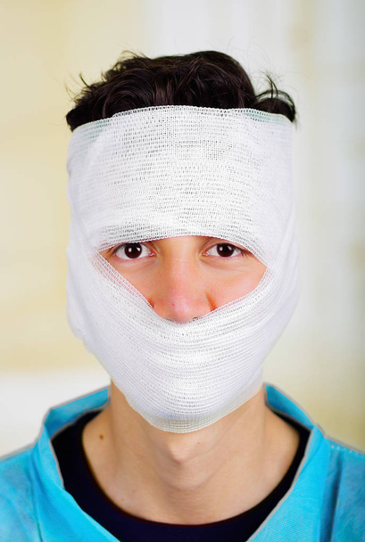 Portrait of a young man with trauma in his head and elastic bandaged around his head - Foto, Imagen