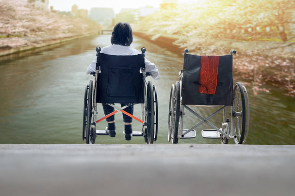 Ηλικιωμένη γυναίκα με άδειο αναπηρική καρέκλα στέκεται μαζί - Φωτογραφία, εικόνα