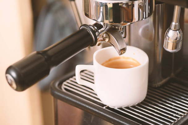Ζεστό καφέ σε ένα φλιτζάνι από μηχανή εσπρέσο - Φωτογραφία, εικόνα