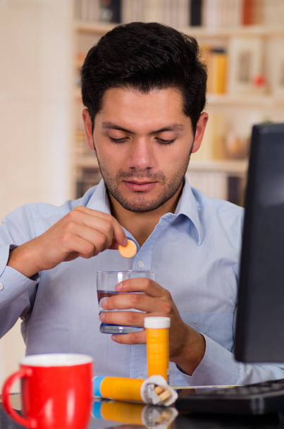 Przystojny mężczyzna opadanie tabletki musującej tabletki w szklance wody - Zdjęcie, obraz