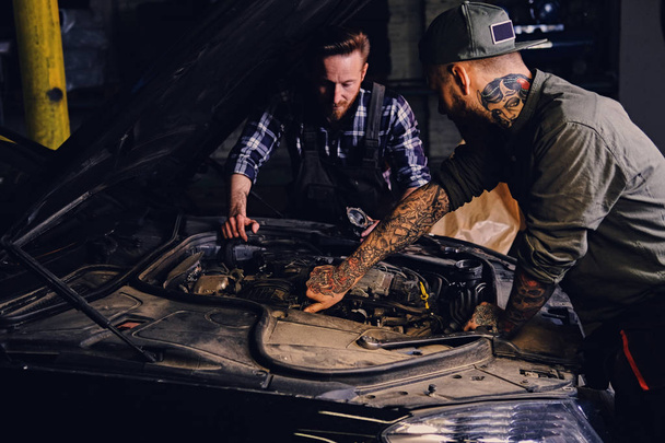 Mecánica tatuada arreglando el motor del coche
 - Foto, imagen