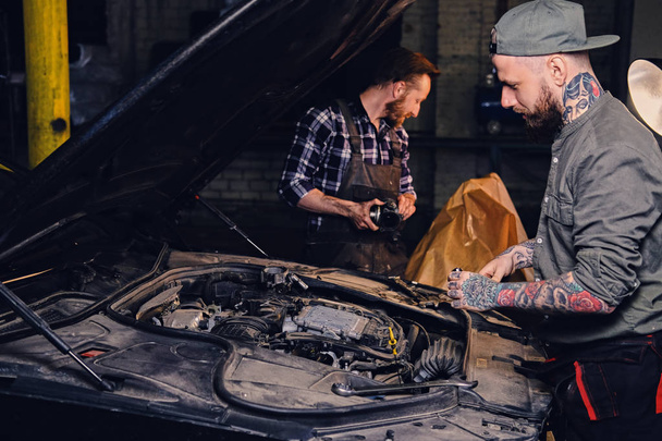 Tattooed mechanics fixing car's engine - Photo, Image