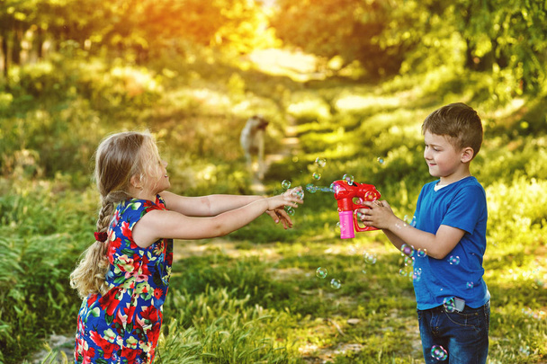 Τα παιδιά παίζουν με σαπουνόφουσκες στο πάρκο στο ηλιοβασίλεμα - Φωτογραφία, εικόνα