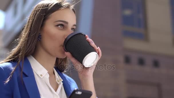 Woman drinks coffee holding an iPhone in her hand - Záběry, video