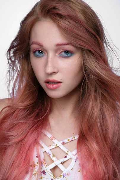 Close-up portrait of beautiful girl with pink hair and pink-and-blue make-up on light background - Foto, immagini