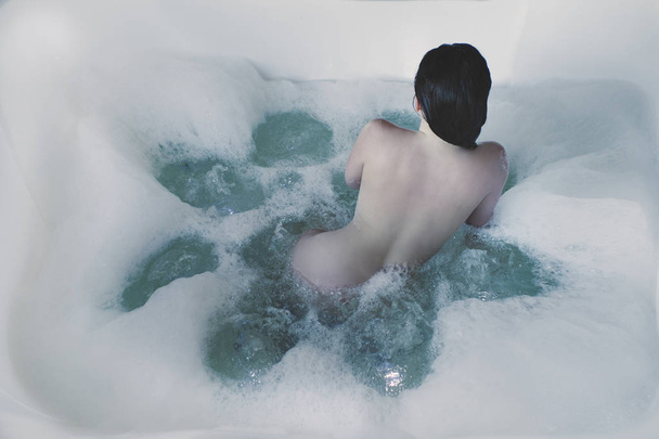 Naked young woman with a large jacuzzi in foam. Girl in the foam in the bathroom - Foto, afbeelding