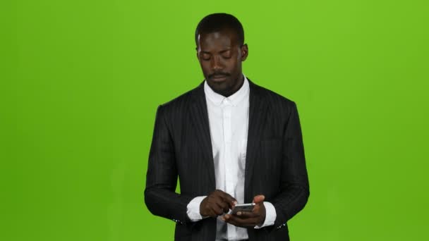 African is holding a phone and flipping through information. Green screen - Video