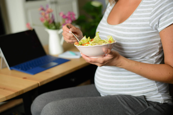 Pregnant woman eating a healthy salad at home - Фото, изображение