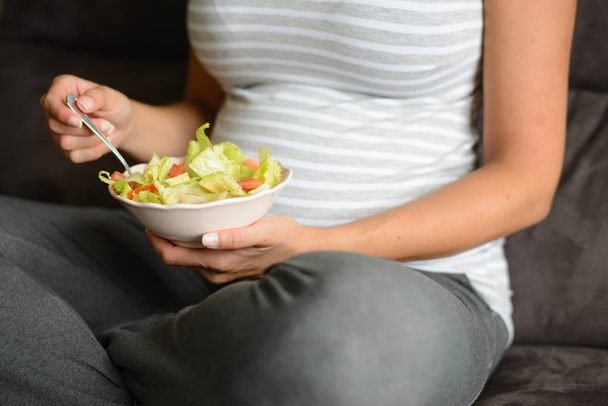 Pregnant woman eating a healthy salad at home - Fotó, kép