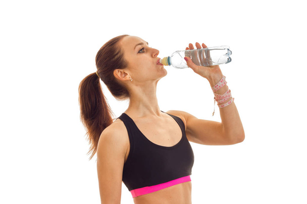 young girl in black top drinks water from a bottle close-up - Foto, Bild