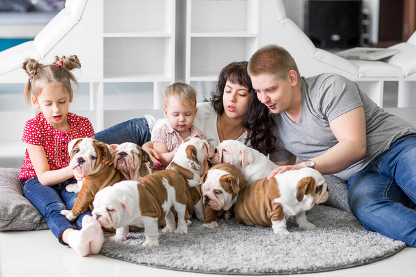 Happy family lying on carpet with puppies of English bulldog - Fotoğraf, Görsel