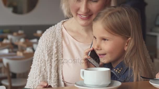Μικρό κορίτσι συνομιλίες σχετικά με το τηλέφωνο στο καφενείο - Πλάνα, βίντεο