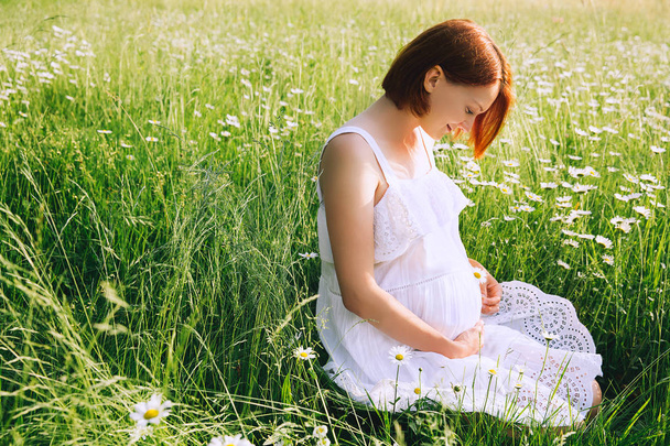 Pregnant woman on nature in chamomile field - Φωτογραφία, εικόνα