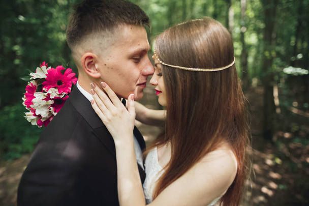 Beautiful young wedding couple is kissing and smiling in the park - Valokuva, kuva