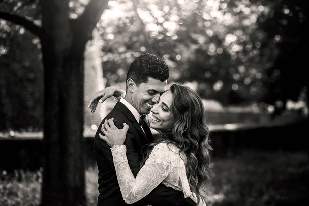 Black and white picture of gorgeous wedding couple hugging on th - Фото, зображення