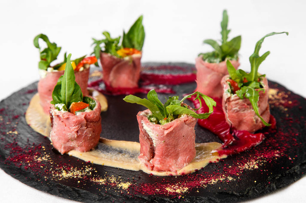Ongewone schotel van vlees rolt met kruiden en sauzen op stenen pla - Foto, afbeelding