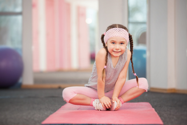 Meisje kind fitness oefeningen in de fitnessclub, die zich uitstrekt in de oefening aan het doen - Foto, afbeelding