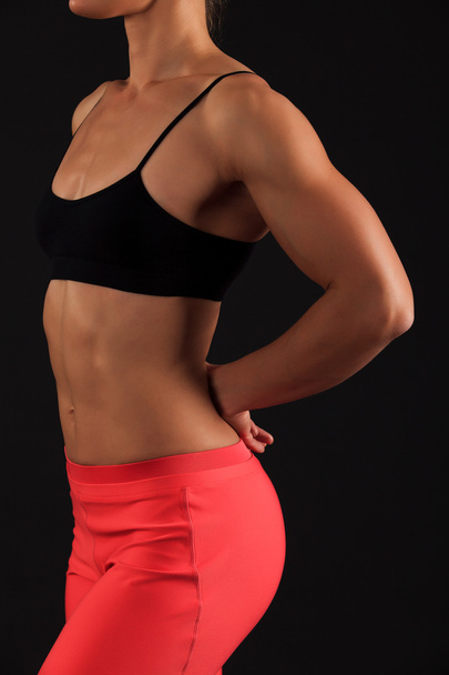 muscular female body against black background. - Фото, зображення