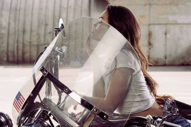Motosiklette oturan genç kadın. - Fotoğraf, Görsel