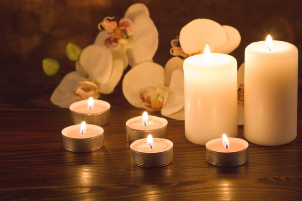 Burning candles and orchid flowers on dark background - Photo, Image