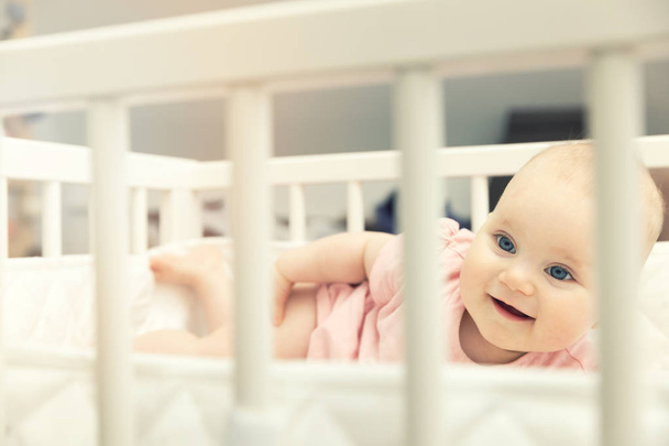 自宅のベッドで横になっている笑顔の幼児ベビー女の子 - 写真・画像