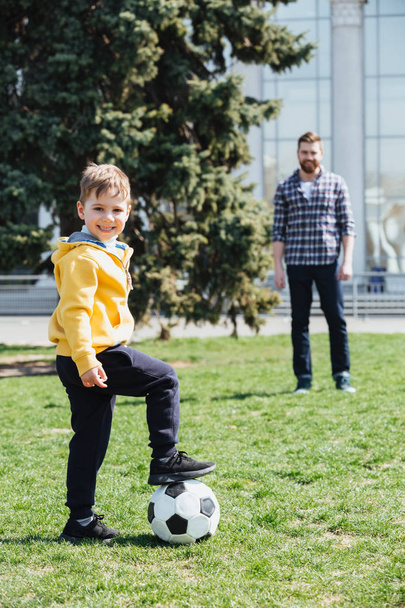 Ładny chłopak, gry w piłkę nożną z ojcem w parku - Zdjęcie, obraz