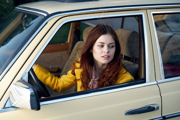 Mooie jonge vrouw in de auto, is een vrouw rijden in een retro auto - Foto, afbeelding