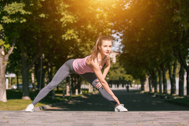 Fit fitness woman doing stretching exercises outdoors at park - Фото, зображення