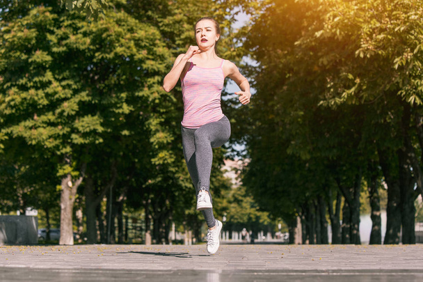 Pretty sporty woman jogging at park in sunrise light - Photo, image