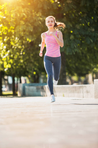Pretty sporty woman jogging at park in sunrise light - 写真・画像