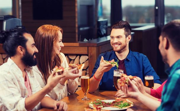 friends eating pizza with beer at restaurant - Photo, Image