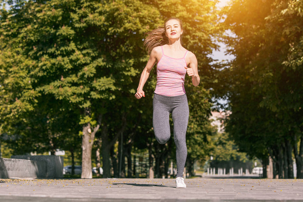 Pretty sporty woman jogging at park in sunrise light - 写真・画像