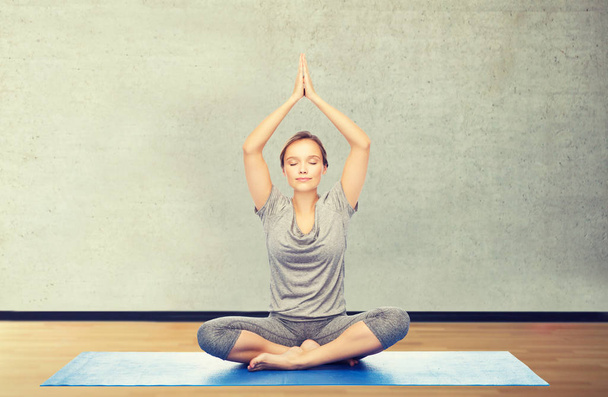 woman making yoga meditation in lotus pose on mat - Фото, изображение
