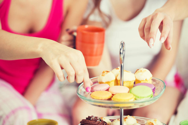 friends or teen girls eating sweets at home - Foto, Imagen