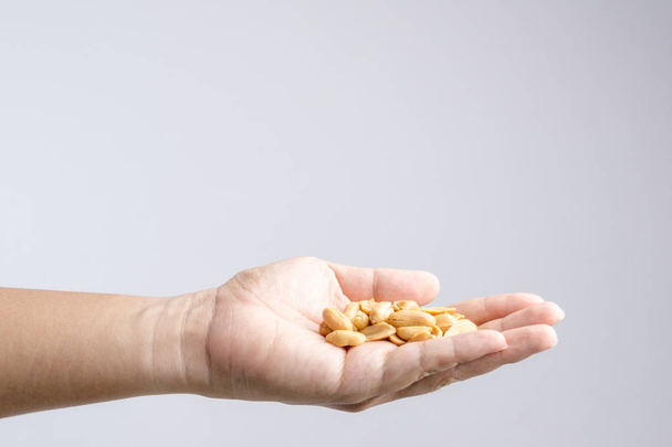 Hand holding heap of salt roasted peanuts - Foto, afbeelding