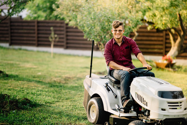 Smiling man riding a lawnmower and doing landscaping works - Foto, Imagem