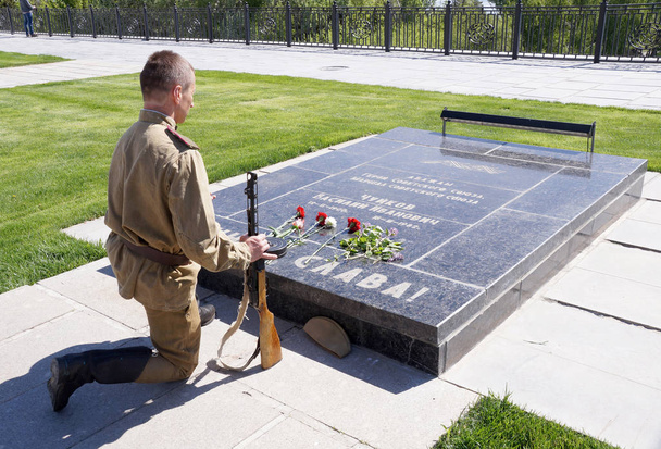 Fighter of Red Army bent a knelt at the grave of Marshal Chuikov - Photo, Image