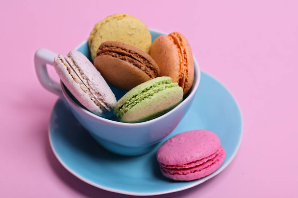 Kolorowe różnych o smaku macaroons w filiżance na różowym tle - Zdjęcie, obraz